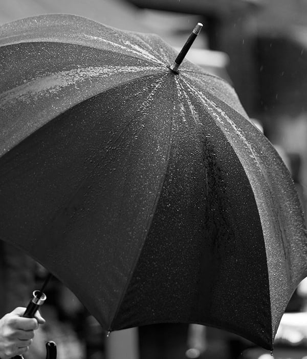 black and white photo of umbrella in the rain