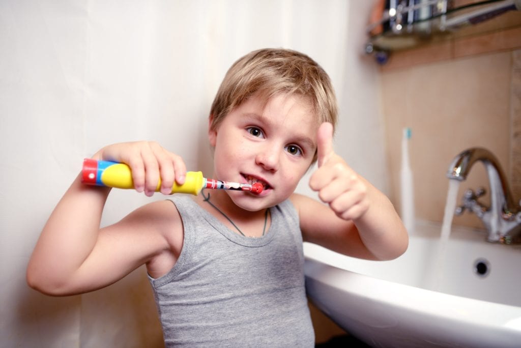 boy brushing his teeth with a thumbs up