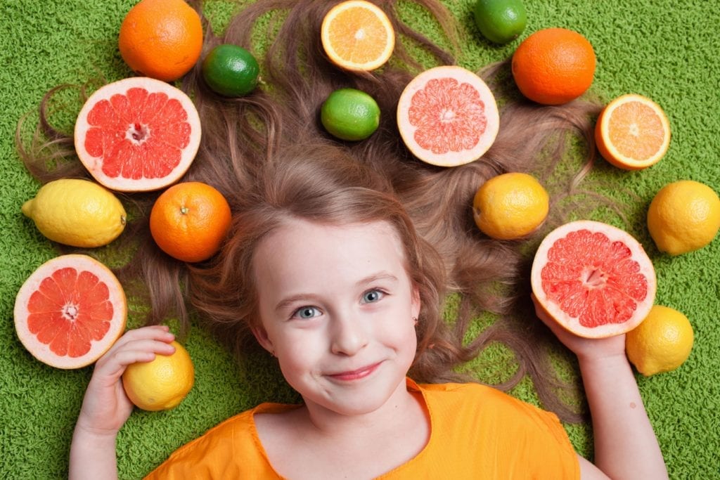 young girl surrounded by citrus