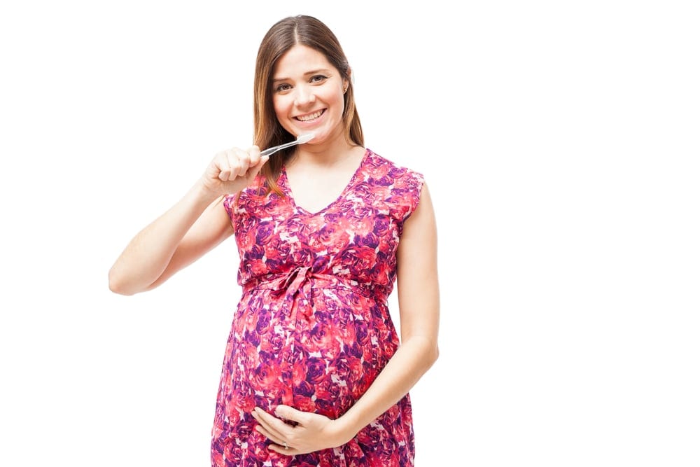 pregnant woman brushing her teeth