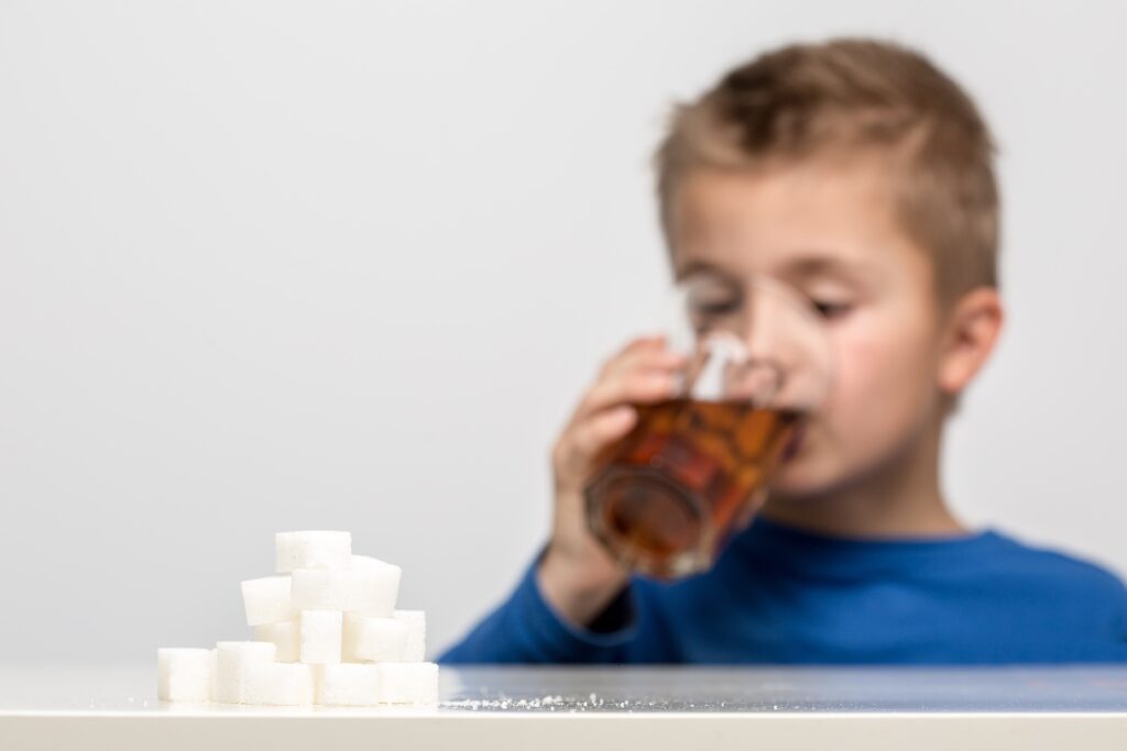 pile of sugar cubes in the foreground with boy drinking soda in the background