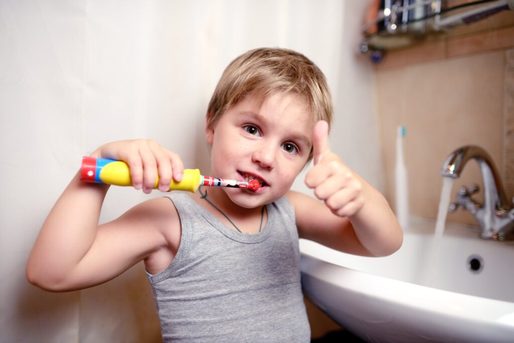 young boy brushing his teeth with an electric toothbrush
