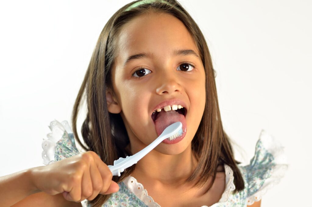 young girl brushing her tongue with toothbrush