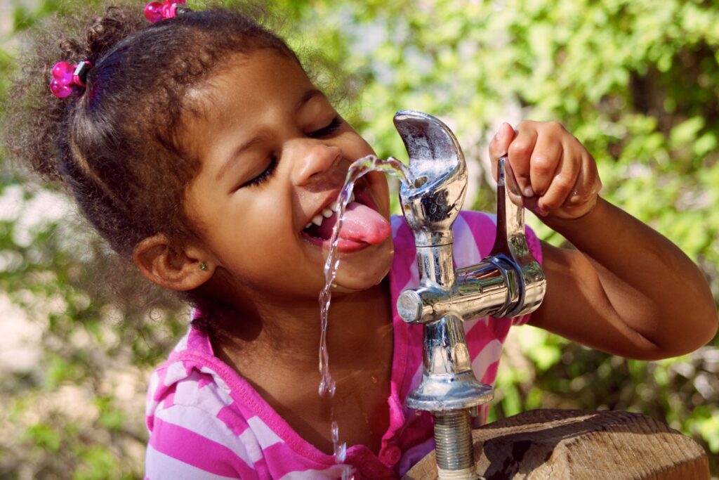 young girl drinking water from a drinking fountain