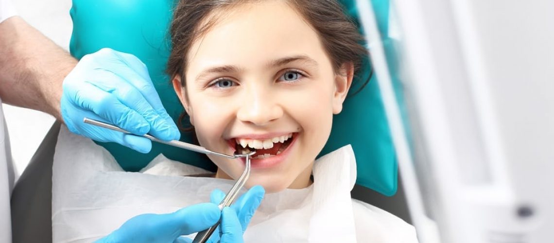 young girl on dentist chair getting her teeth cleaned